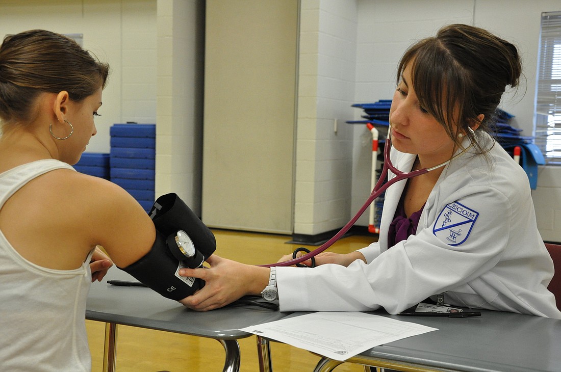 Third-year LECOM medical student Tammy Gebo-Seaman, right,  takes Taylor Hoyt's blood pressure. Photo by Michael Polin.