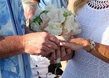 Admiral Steve Branham slides the wedding band onto Susanâ€™s ring finger.