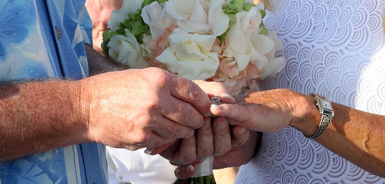 Admiral Steve Branham slides the wedding band onto Susanâ€™s ring finger.