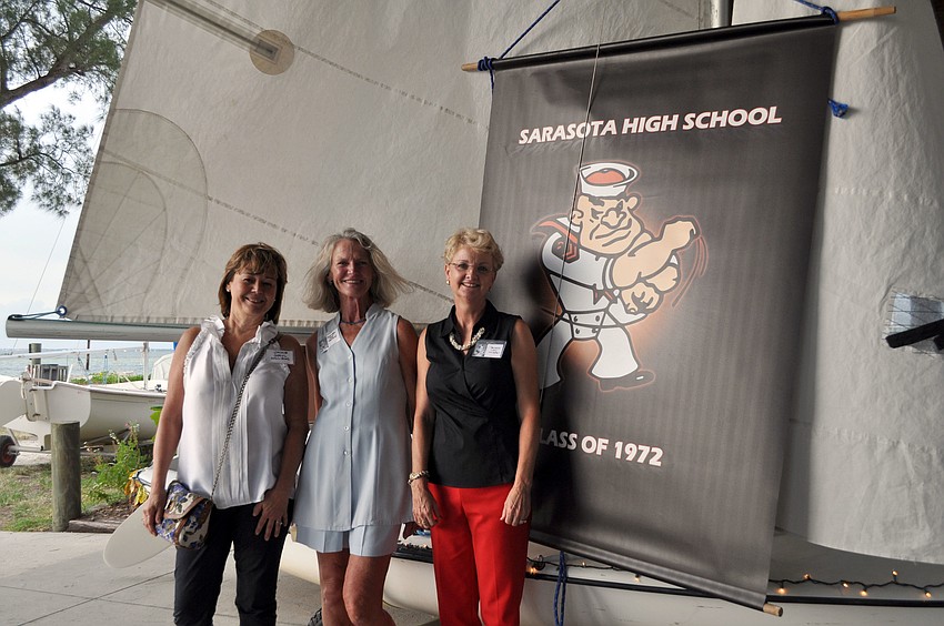 Jackie Goryl Williams, Marinda â€œZoeâ€ Holland and Pamela â€œJoyâ€ Whitesell pose in front of a sailboat with a SHS banner during the kickoff to their 40th high school reunion weekend, Friday, Aug. 3, at the Sarasota Sailing Squadron.