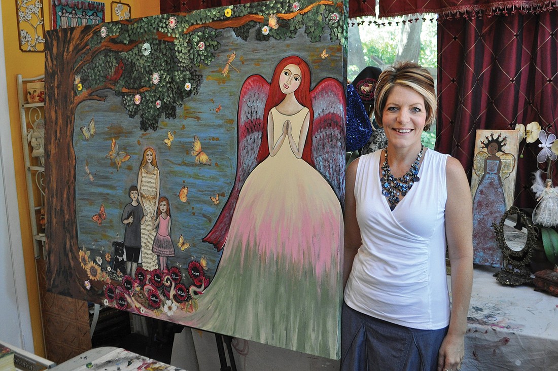 Tonya Smith stands next to a recently completed commissioned painting in her home studio, Moondance Art and Design Company.