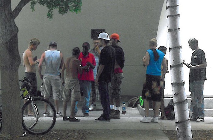 A group of homeless people sit directly across the street from Tsunami Sushi & Hibachi Grill. The restaurant's owner, who was attacked by a man in July, says their presence has dropped his profits by as much as 60%.