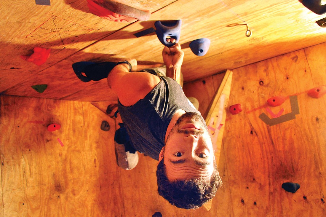 Sean Morris hangs from the ceiling of his homemade cave rock-climbing wall.