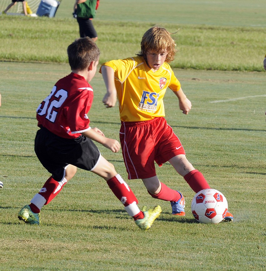Ten-year-old Clearwater Chargers midfielder John Stinette tries to dribble past a Wesley Chapel Flames defender.