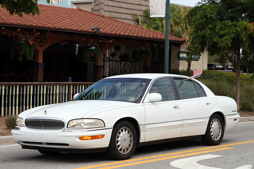 A car drives through Siesta Key Village Tuesday, Sept. 11, with a small American flag sticking out of the back, driver-side window.