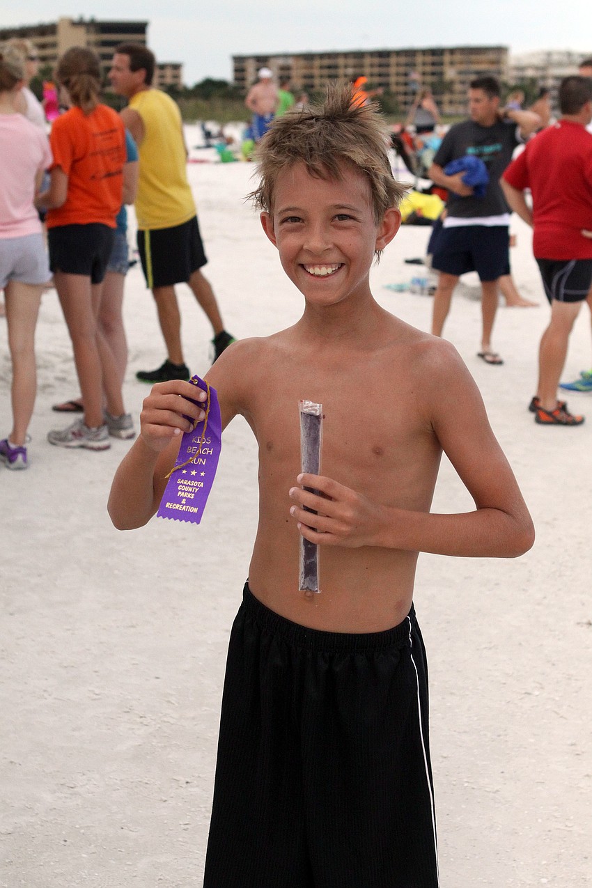 Spencer Douberly, 12, shows off his ribbon and ice pop after finishing the second Summer Fun Run of the season, Tuesday, June 19, out on Siesta Key Public Beach.