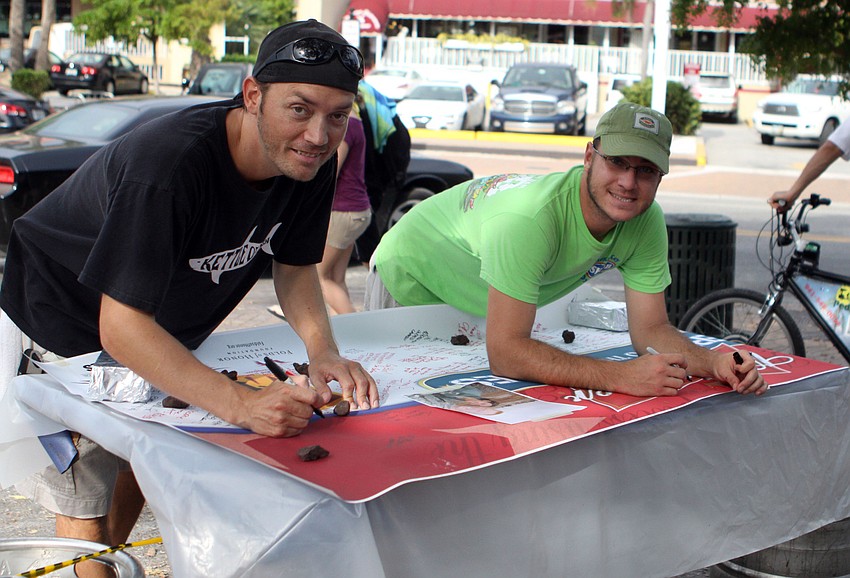 Gabriel Fassler and Milton Bontragor sign the banner, Wednesday, July 4, at Siesta Key Oyster Bar.