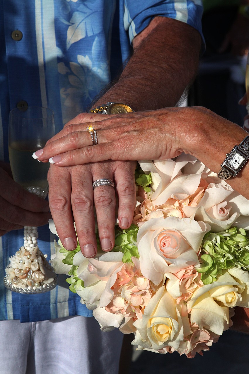 Admiral Steve and Susan Branham show off their wedding rings and Susanâ€™s bouquet for a wedding photo on Saturday.