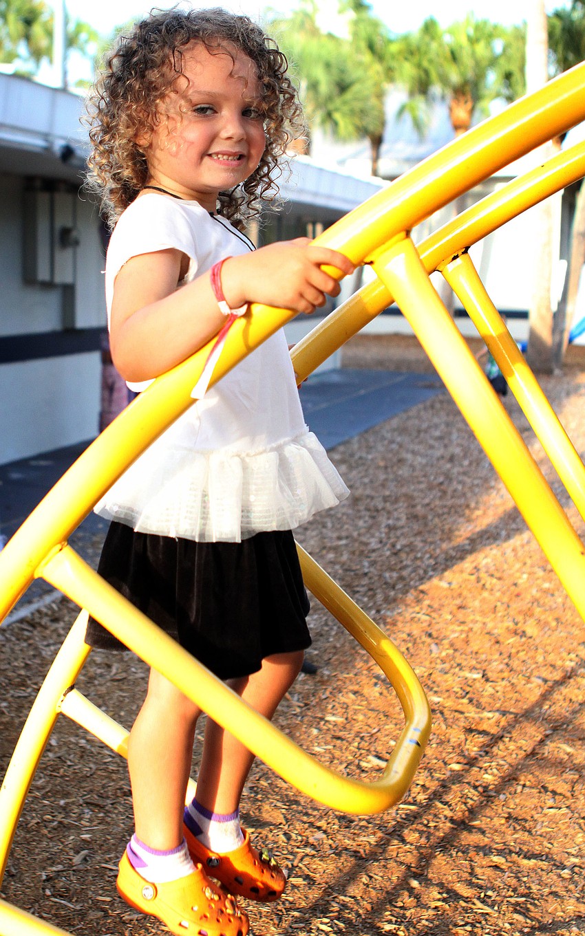 Kirin Singer, 5, climbs up a curved ladder on the playground.