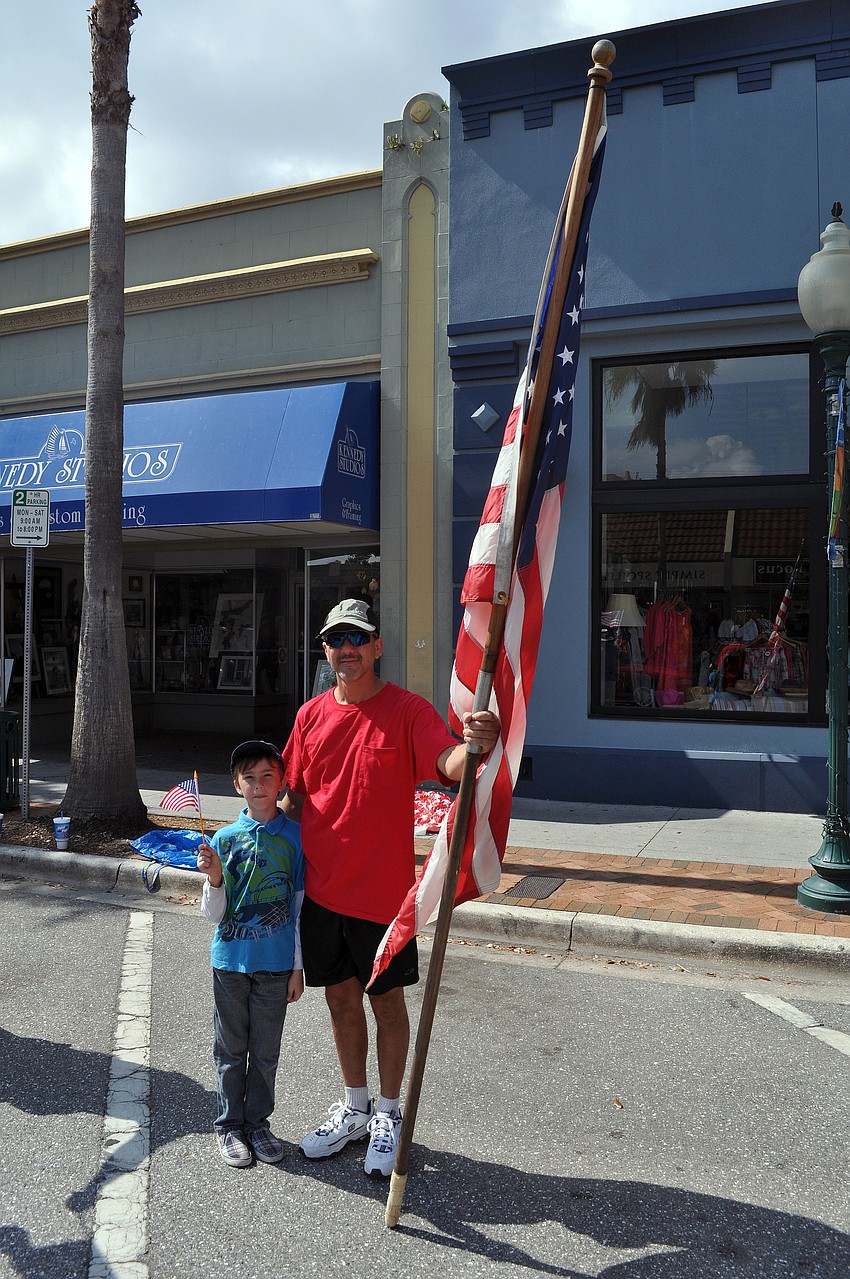 Rhett Thirion, 7 Â¼, waves his small American flag while his father, Scott, holds onto a large American flag.