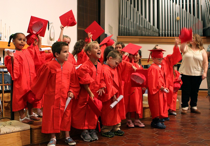 The students throw their caps in the air after a little bit of coaxing from their parents.
