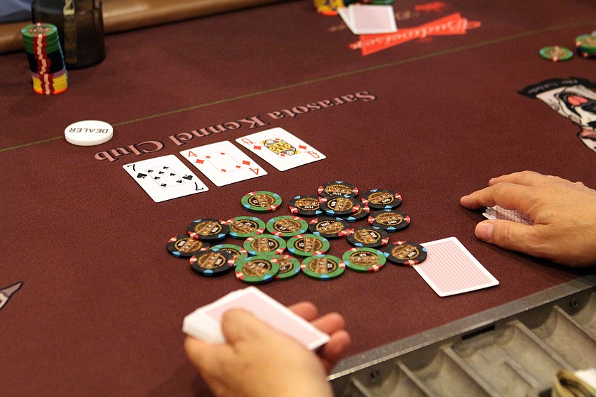 One of the dealers shows three cards and waits to see what the players will do, Thursday, June 7, during the Siesta Key Chamber of Commerce Poker Tournament.