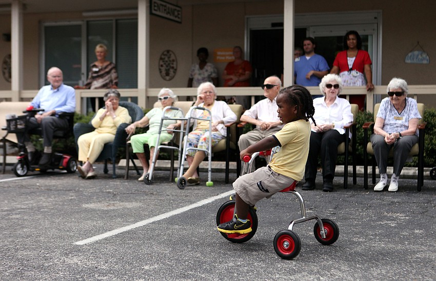 DJ Porter, 2, rides by some of the residents of the Pines of Sarasota on one of the new tricycles, Tuesday, Aug. 7.