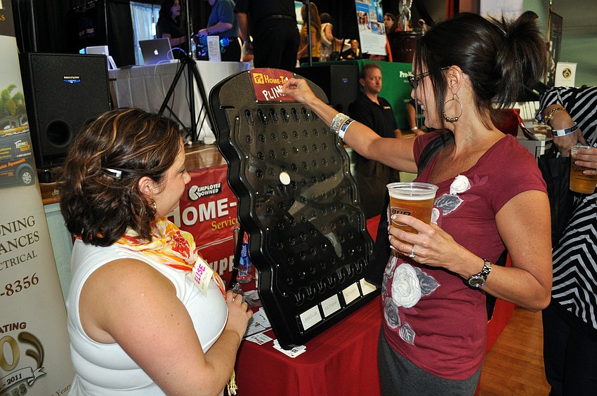 Elise Lipoff watches as Shari McDuffie plays Home-Tech's Plinko game Wednesday, Sept. 5.