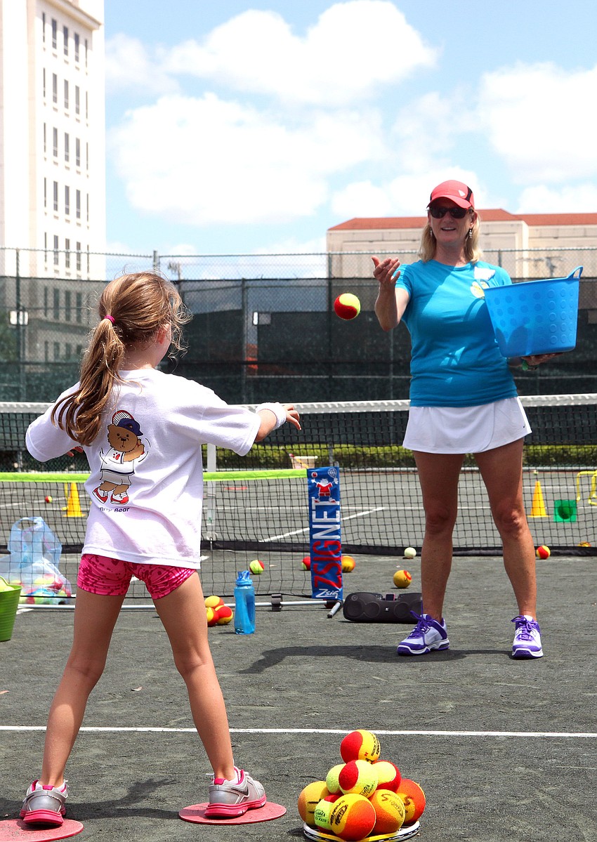 Lark Baxter, of Teddy Tennis, throws a ball to Hayley Roberts, 6, Saturday, June 16.