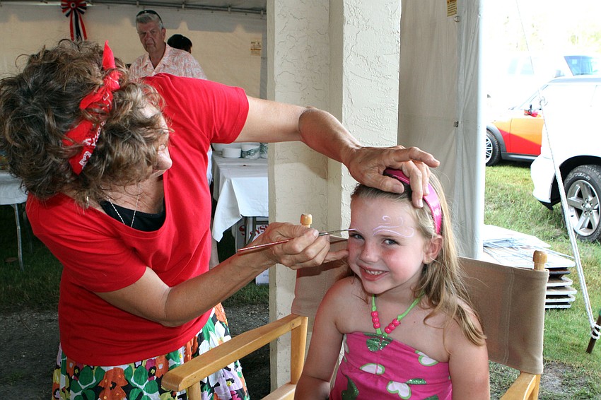 Judy Eidge paints patriotic curly-q's on Olivia Henderen's, 6, face at the VIP Party, Wednesday, July 4.