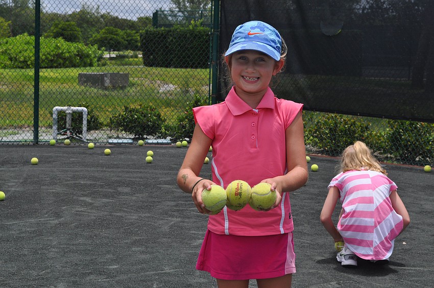 Clementine Schwartz, 7 Â½, helps to pick up balls after running hitting drills on Monday afternoon.
