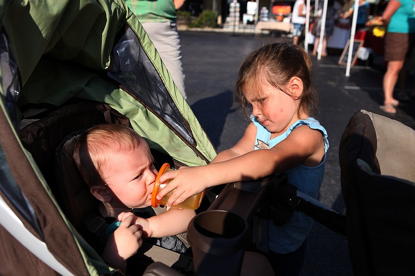Lydia Shannon, 2 Â½, helps her brother, Isaac, with his sippy cup while wandering around the Siesta Key Farmers Market Sunday, Sept. 1.