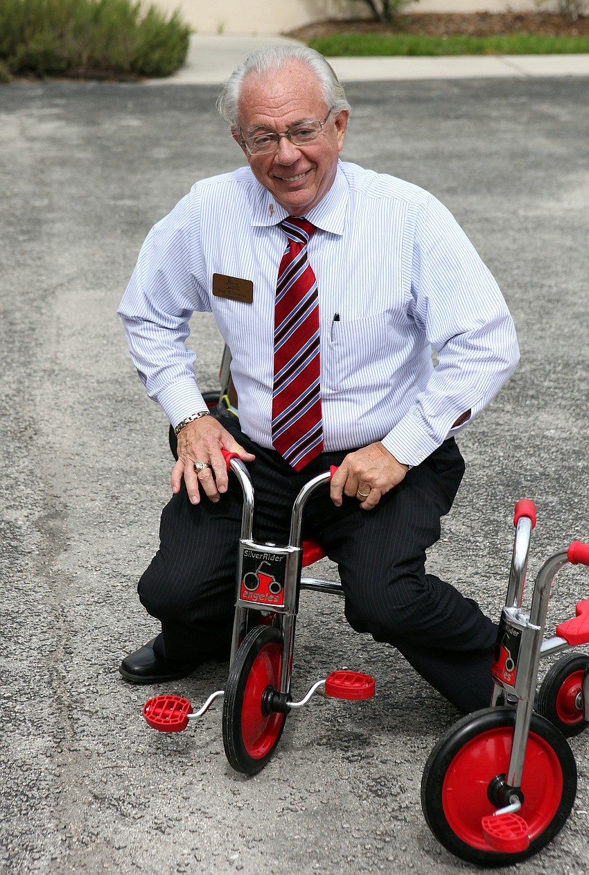 John Overton, President of Pines of Sarasota, tries to ride one of the new tricycles.