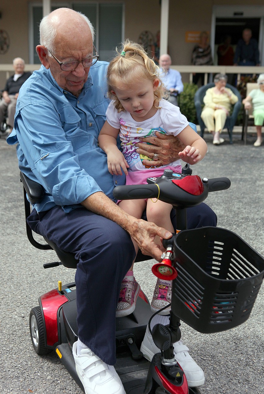 Bob Ireland shows Rylee Wyant, 2, the horn on his scooter.