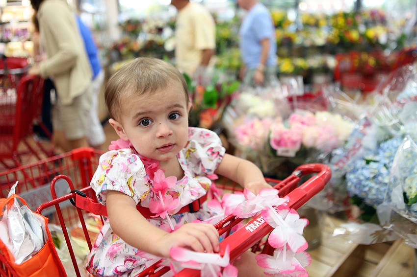 Evelyn Sampson, 16 mos., has fun playing with some leis.