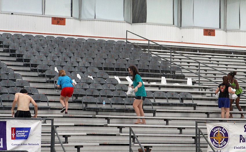 Participants run out in the rain in an attempt to save the luminaries that were to be lit to say â€œHOPEâ€ in the stands.