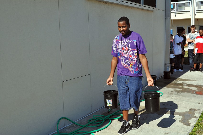 Roseman Alexis practices carries buckets of water to show how much difficult it is for some people to access drinking water.