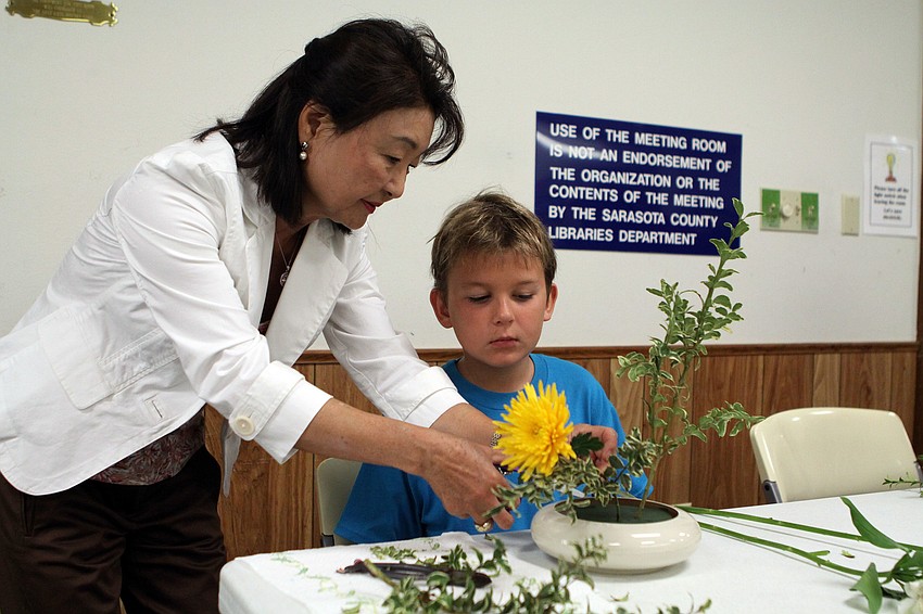 Sensei Yukiko Brown helps Michael Postranecky, 9, with his Ikebana flower arrangement, Saturday, May 12, at Gulf Gate Library.