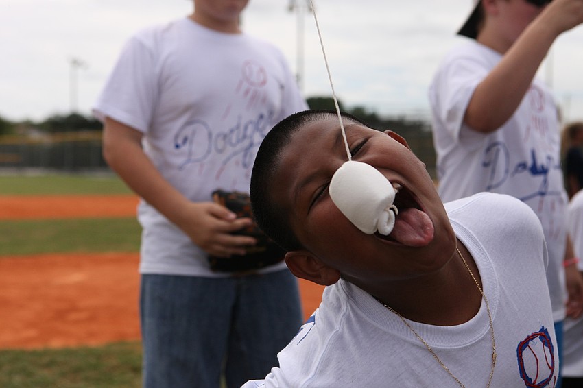 Jose Alonzo, 11, tries to eat a marshmallow off a string with his hands behind his back during a game in between innings, Friday, May 4, at Twin Lakes.