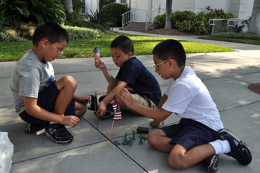 Nathan, 7, Zachary, 5, and Gabriel, 7, Alpert play with their toy soldiers and flags while waiting for the parade to start, Monday, May 28.