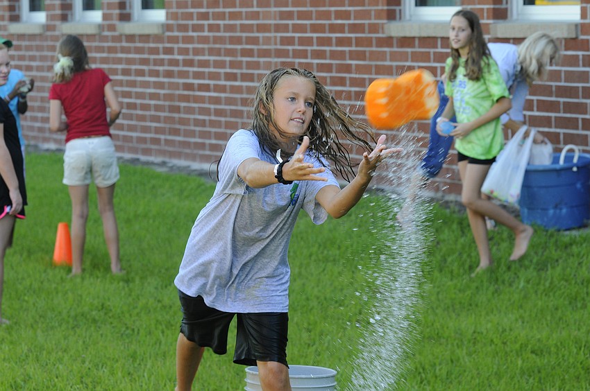 Eleven-year-old Presley Thompson throws a soaking wet sponge to a teammate during the relay race.