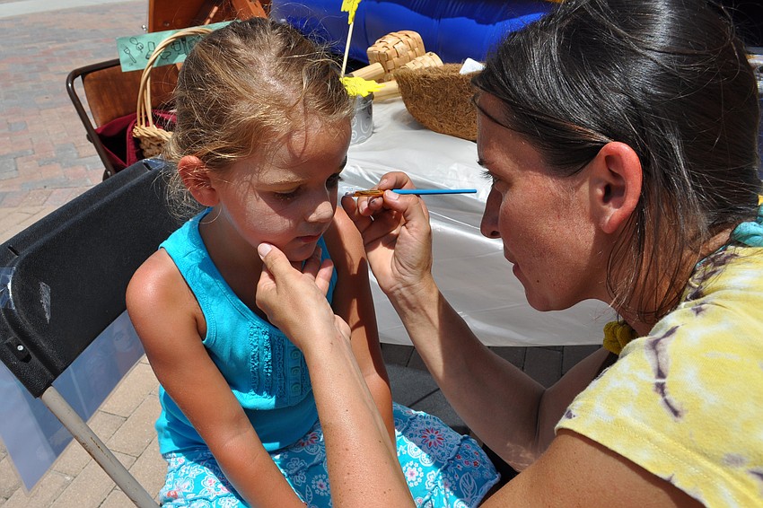 Lina Nier, 5, get her face painted by Krisztina Ihaszy.