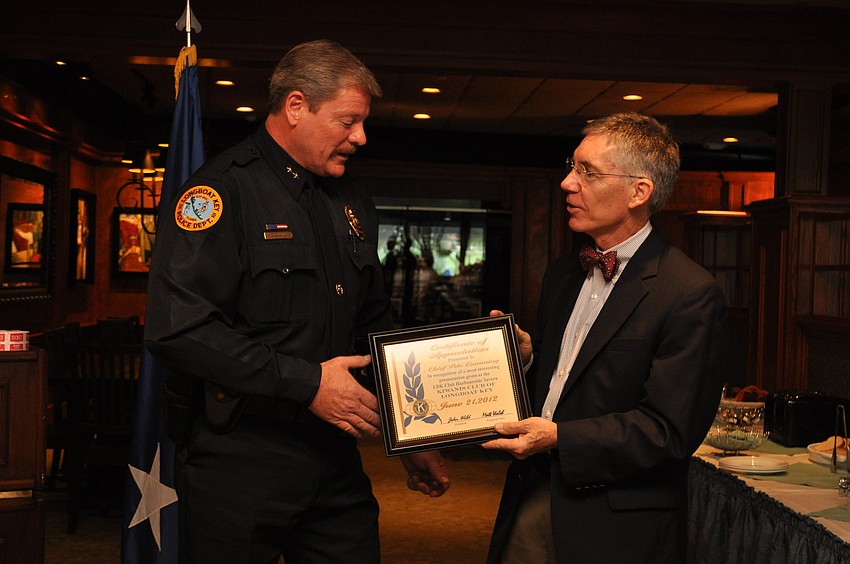 Interim Police Chief Pete Cumming is awarded with a plaque by Matt Walsh.