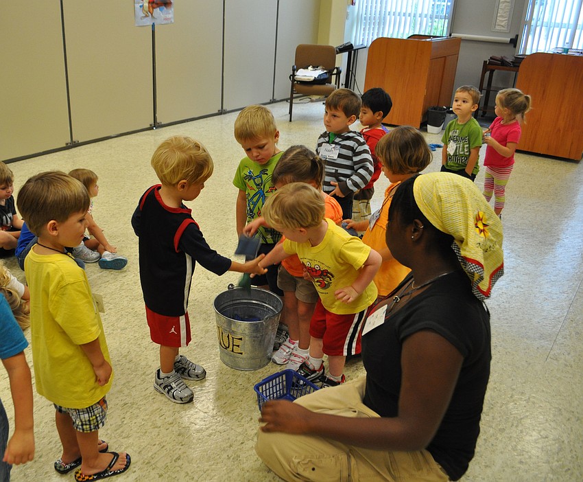 Students take turns tossing beanbags into buckets.