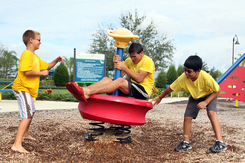 Noah Bean, 10, and Matthew Garcia, 10, have fun spinning camp counselor Caleb Suttle around, Wednesday, July 18, out at Central Park.