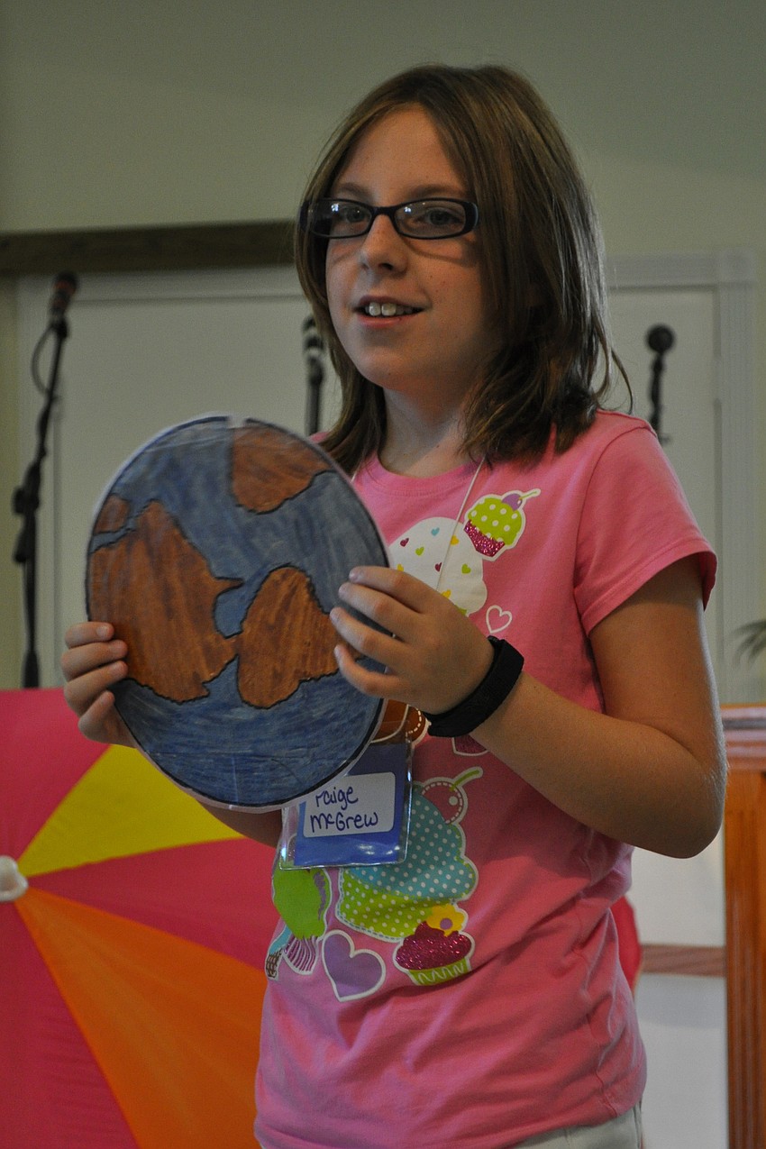 Paige McGrew, 10, held a picture of the world as children sang 