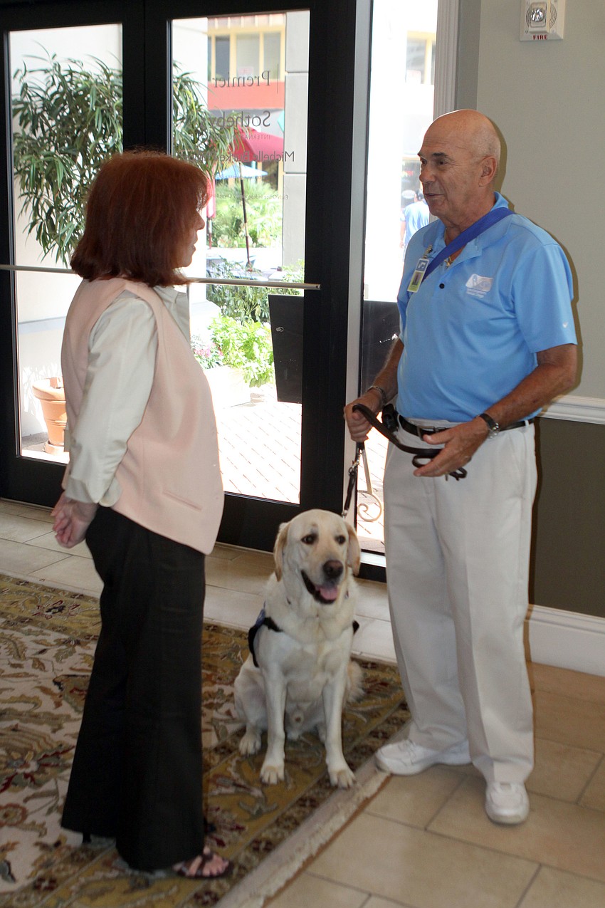 Jackie Becher and Mike Miller chat while Squire sits between them, Thursday, July 26, at Premier Sothebyâ€™s.