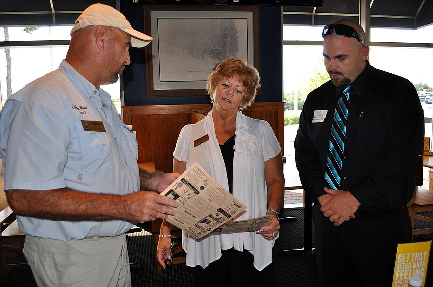 Ed Koehler of Coffee News shows Pat Martin and Shaun Martin of Pampered Movers a copy of Coffee News during the Siesta Key Chamber luncheon Friday, Oct. 7 at Buffalo Wild Wings.