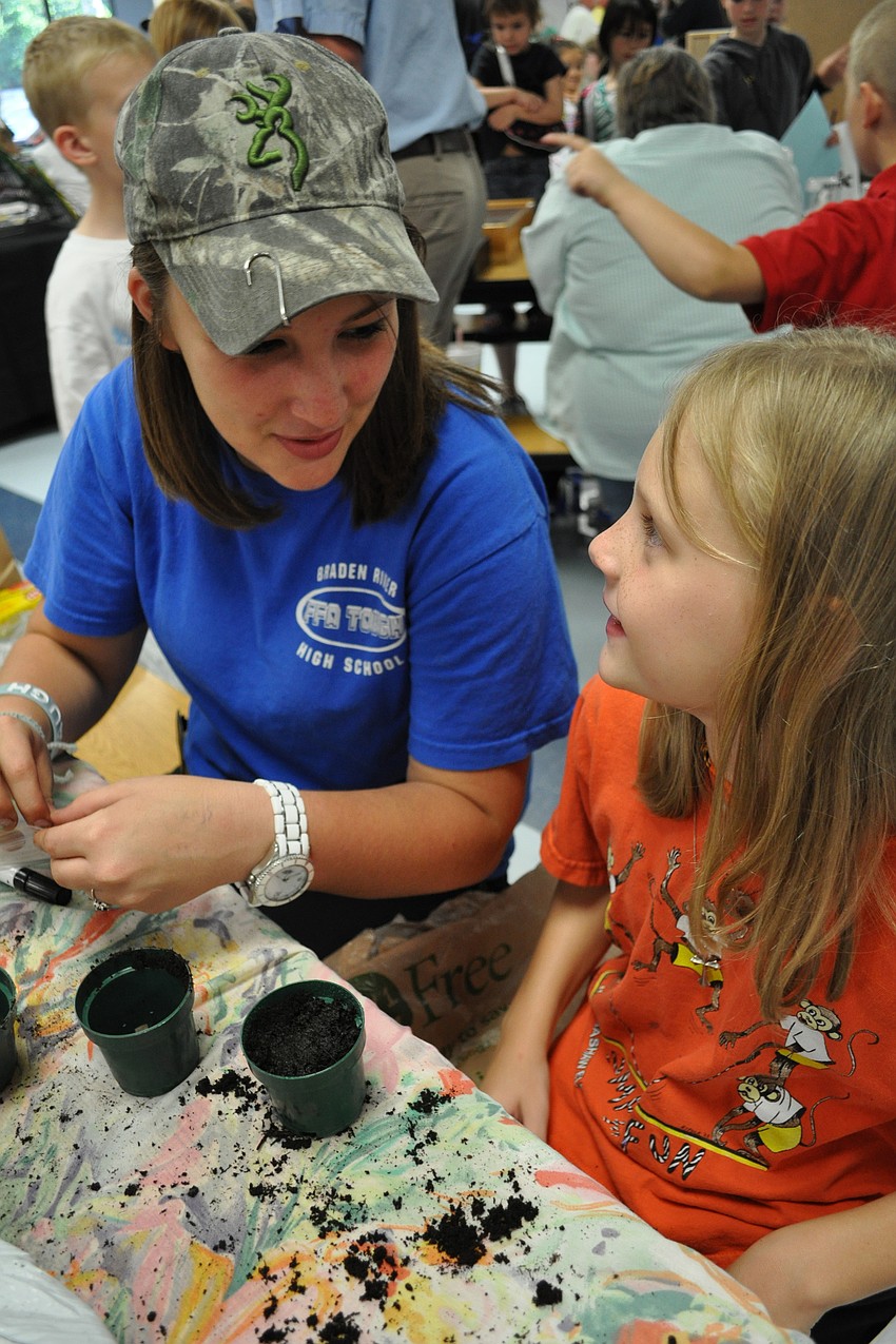 Braden River High School student Samantha Thornton helped Maggie Donnelly, 8, plant a lima bean.