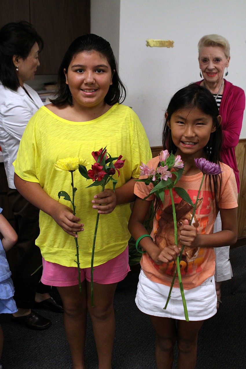 Marisol Cruz, 11, and Rachel Hamer, 9, show off the flowers they picked out to use for their flower arrangement.