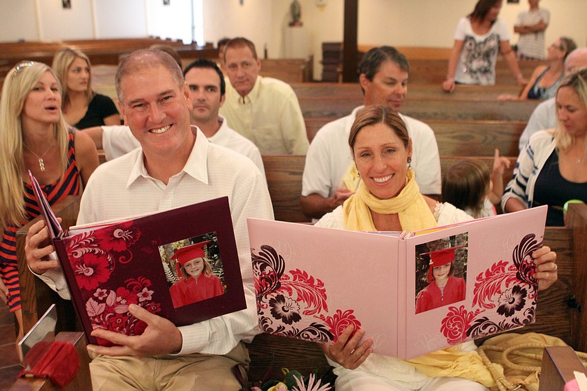 John and Eva Macaluso show the scrapbooks of their twin daughters Chloe and Claire that they were given by the teachers as part of graduation.
