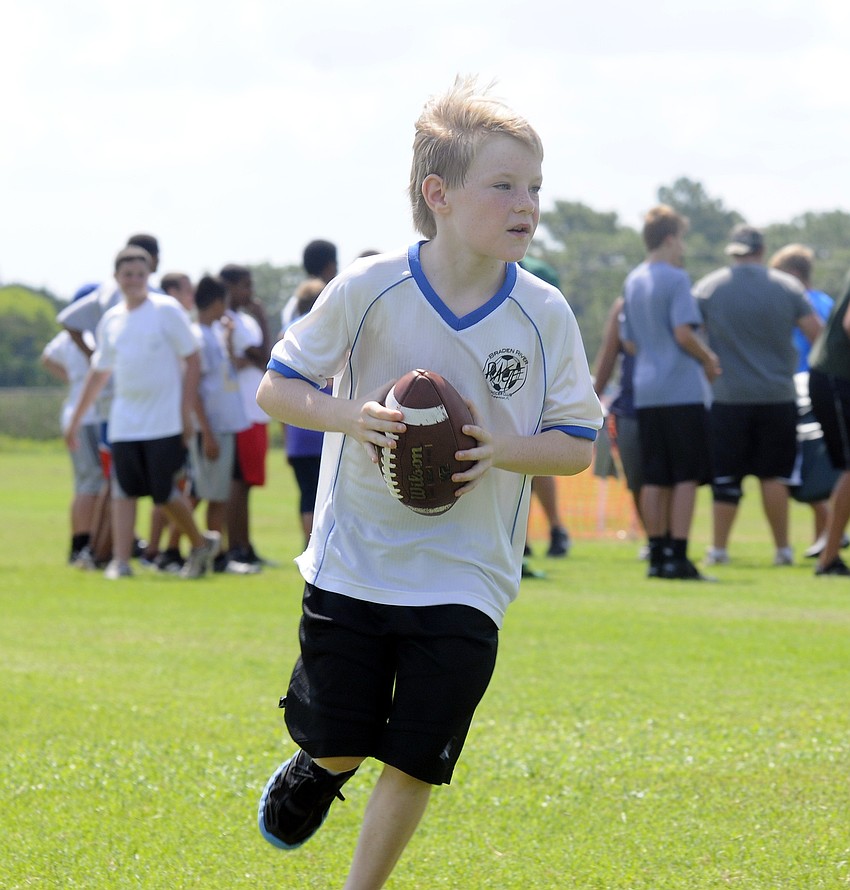 Nine-year-old Hunter Simpson drops back for a pass during a quarterback drill.