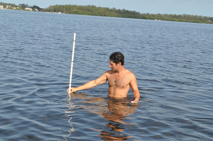 Volunteer Justin Bloom measures the depth of the water