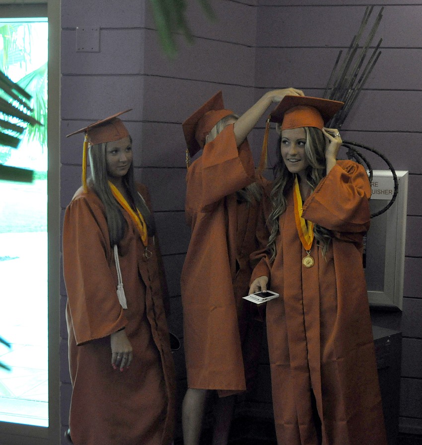Students help each other adjust their hats before the ceremony.