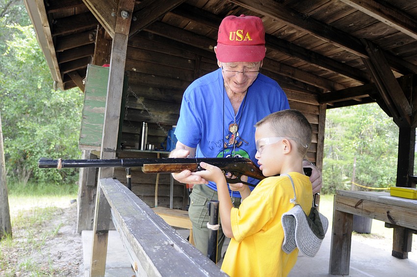 Red Dog helps seven-year-old Sebastian Collado at the BB gun range.