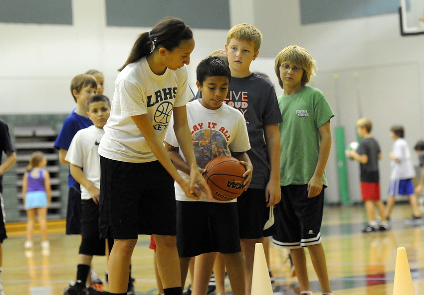 Lakewood Ranch Highâ€™s Elise Spiller goes over a ball-handling drill with 12-year-old Jonah Mazzone.