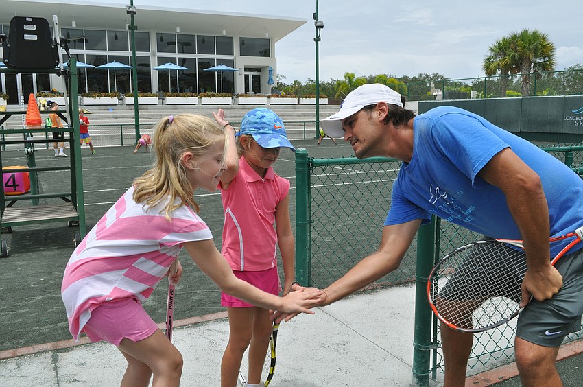 Coach Todd Scheck gets double low-fives from Alexia Pasold, 8 Â½, and Clementine Schwartz, 7 Â½, before starting drills.