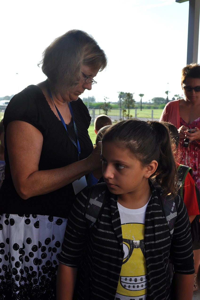 Gullett Guidance Counselor Monica Rice helped put a tag on the backpack of Marissa Valencia, 10, who will be picked up by car each day.