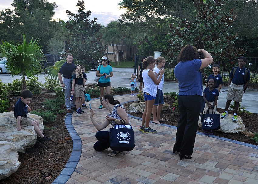 Parents photograph their students in front of rocks, trees and bushes before walking in for the first day back to school, Wednesday, Aug. 22.