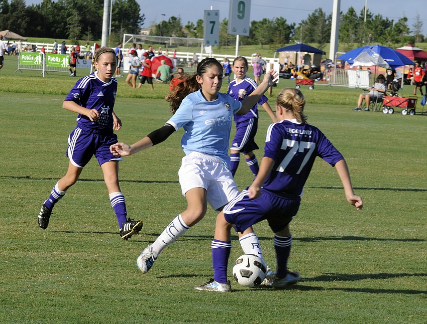 Eight-year-old Helena Torres, center, battles an Orlando City Soccer opponent for the ball.